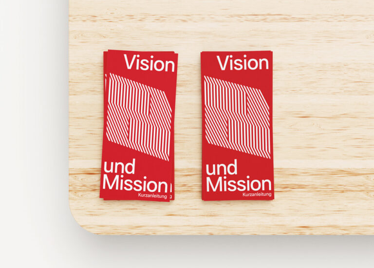 Die Kurzanleitung "Vision und Mission" liegt in zwei Stapeln auf einem Tisch
